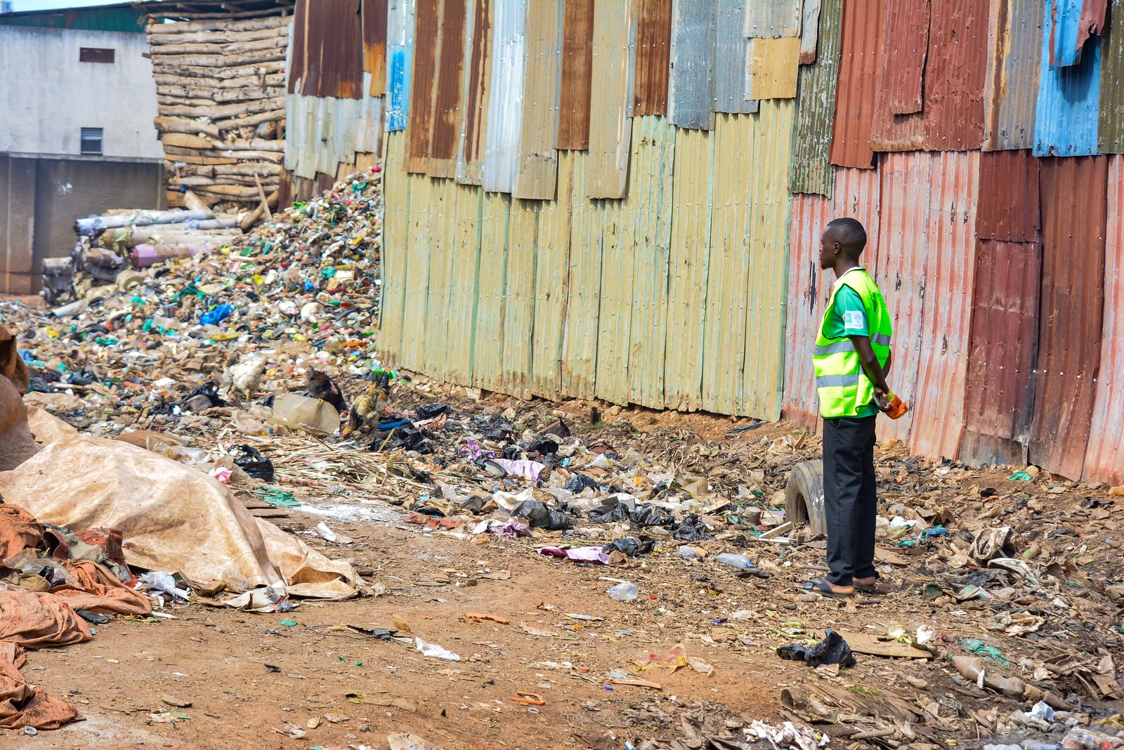 A worker in a high-visibility vest standing beside a waste site