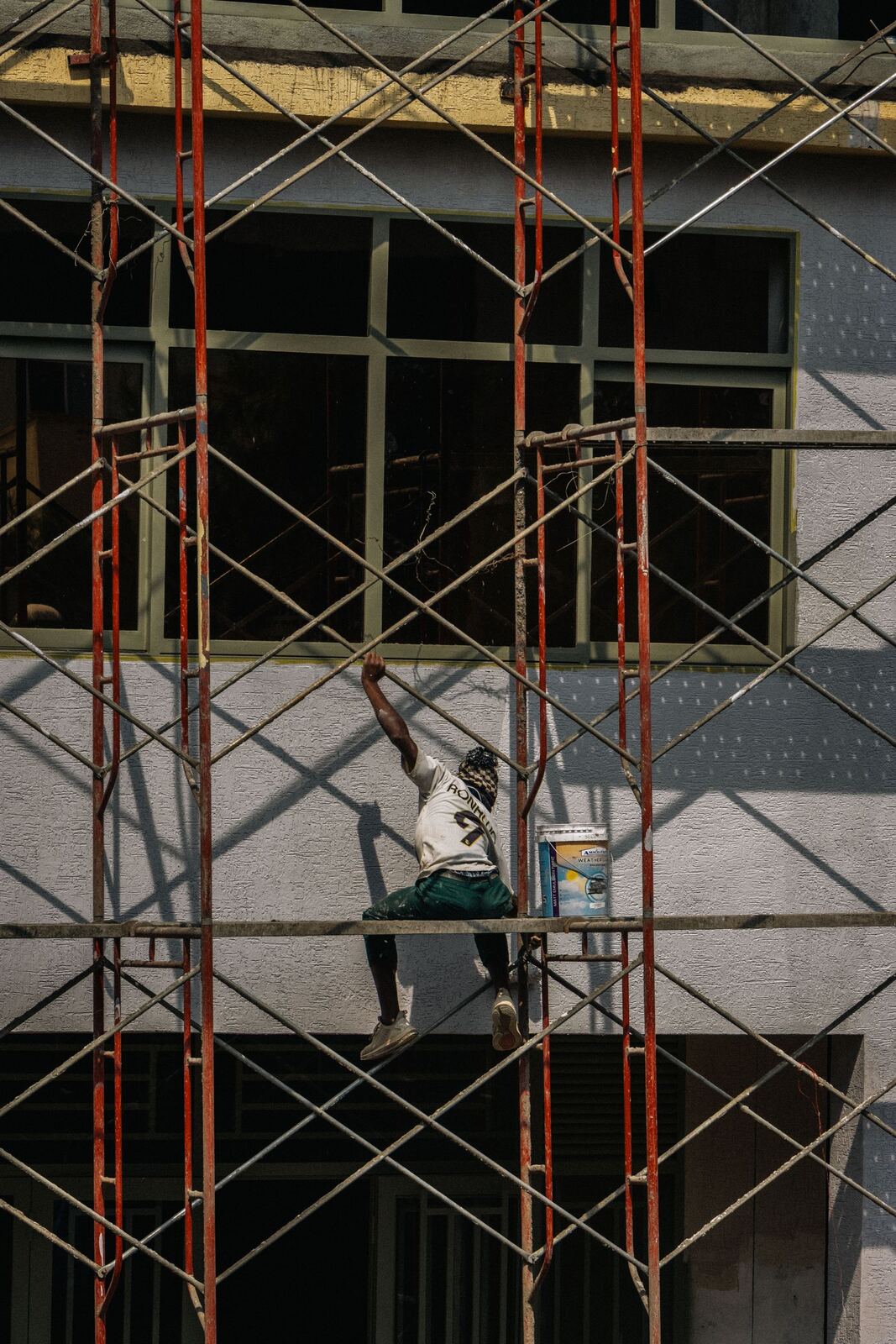 Worker painting a building facade from scaffolding