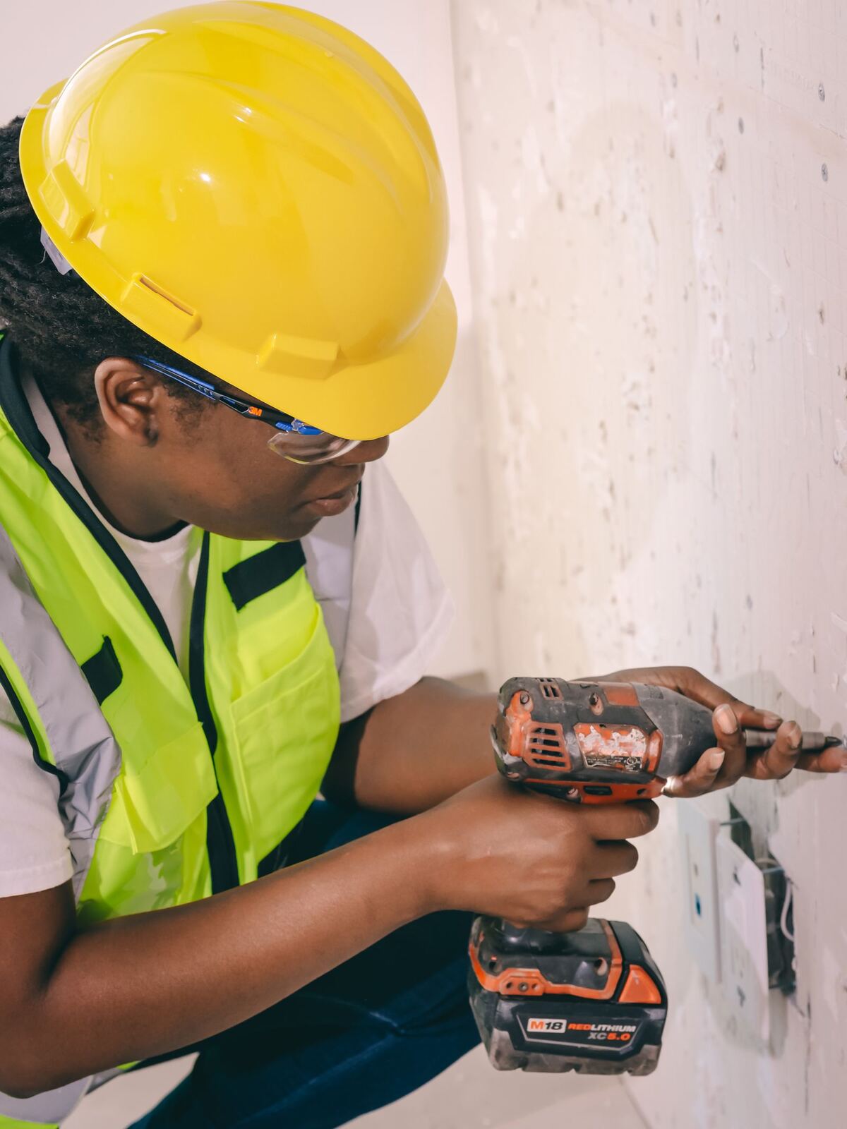 Worker in safety gear operating a power drill indoors