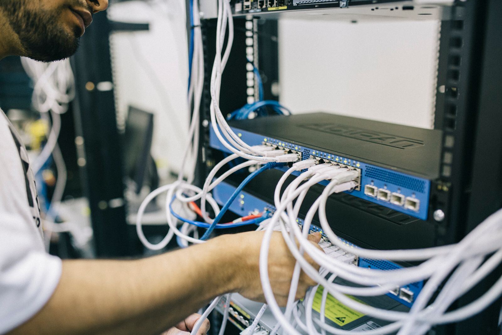 Technician configuring Ethernet cables in a network rack