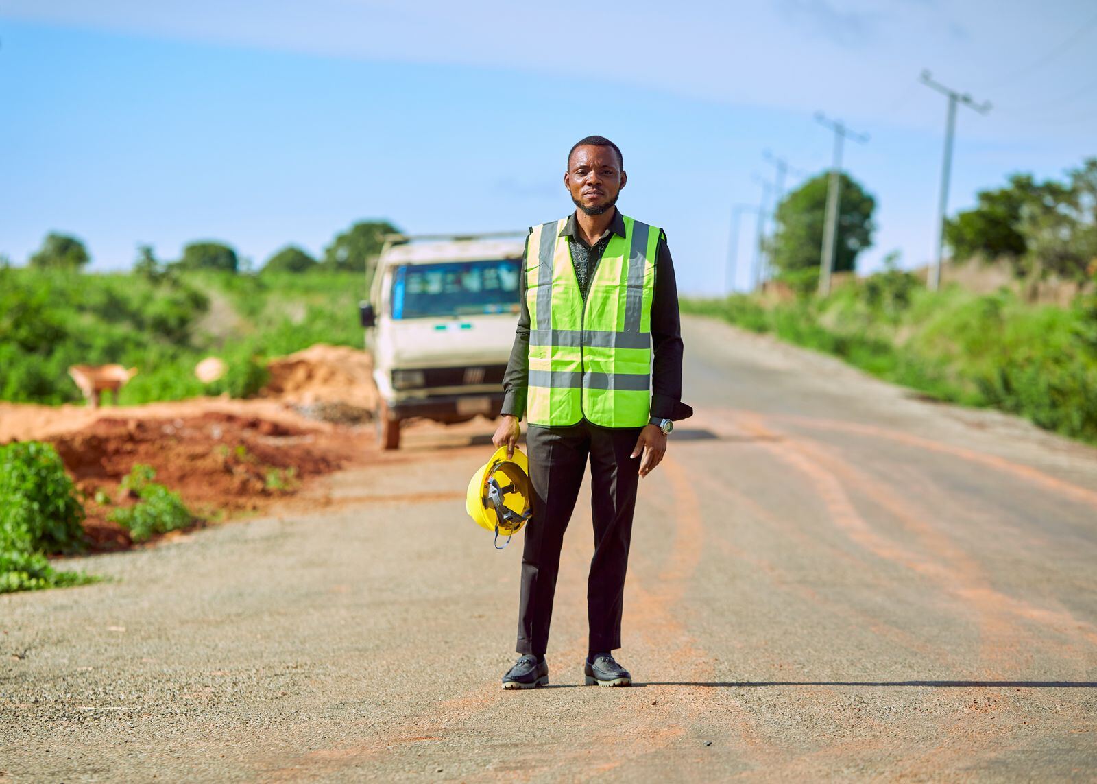 Road worker in a safety vest standing on a rural road
